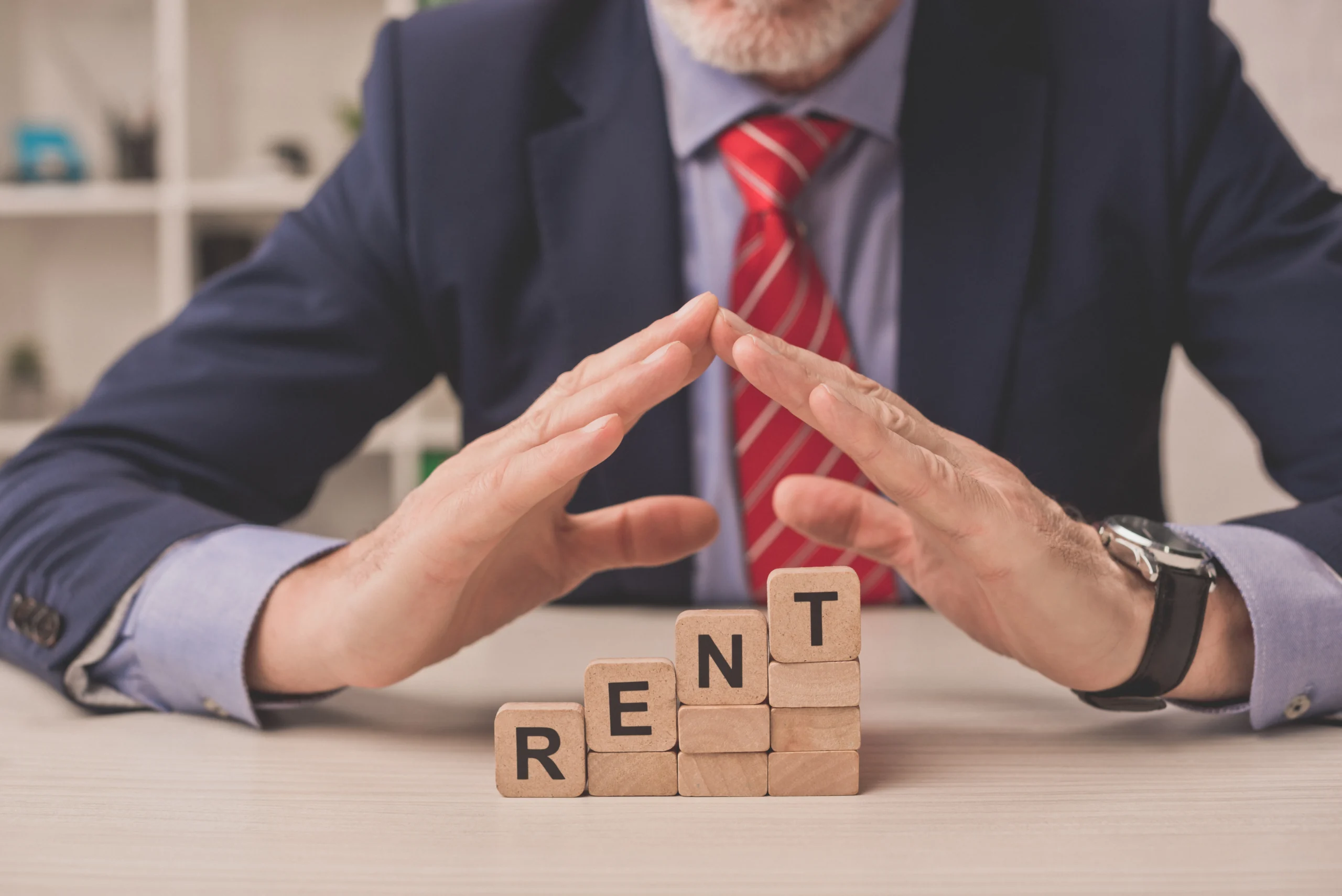 agent putting hands above wooden cubes with rent lettering